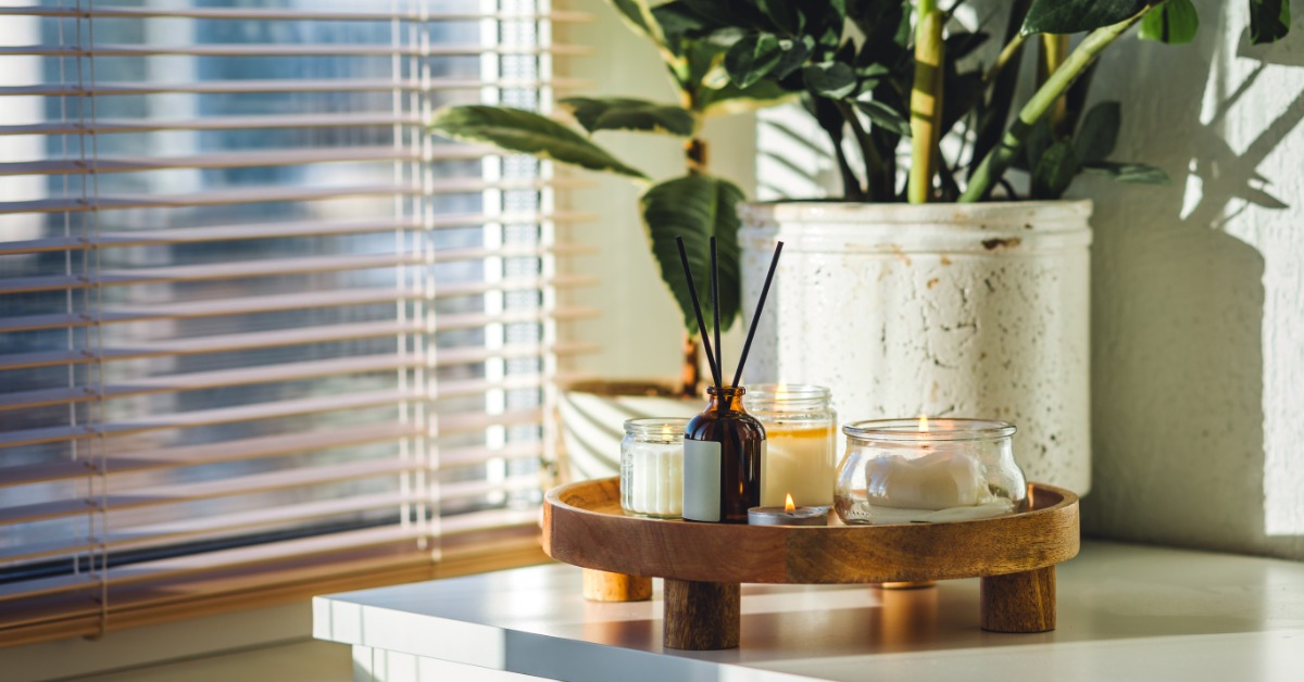 A tray sits on the dresser next to the window. The blinds are open and the candles on the tray are lit.