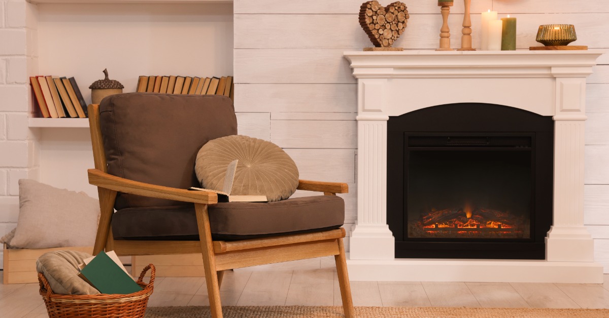 A brown accent chair next to a white fireplace surround. The mantel has various sized candles burning.
